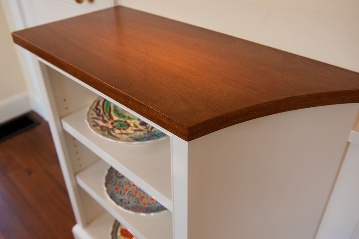A photo of a cabinet with wood countertop and open shelving.