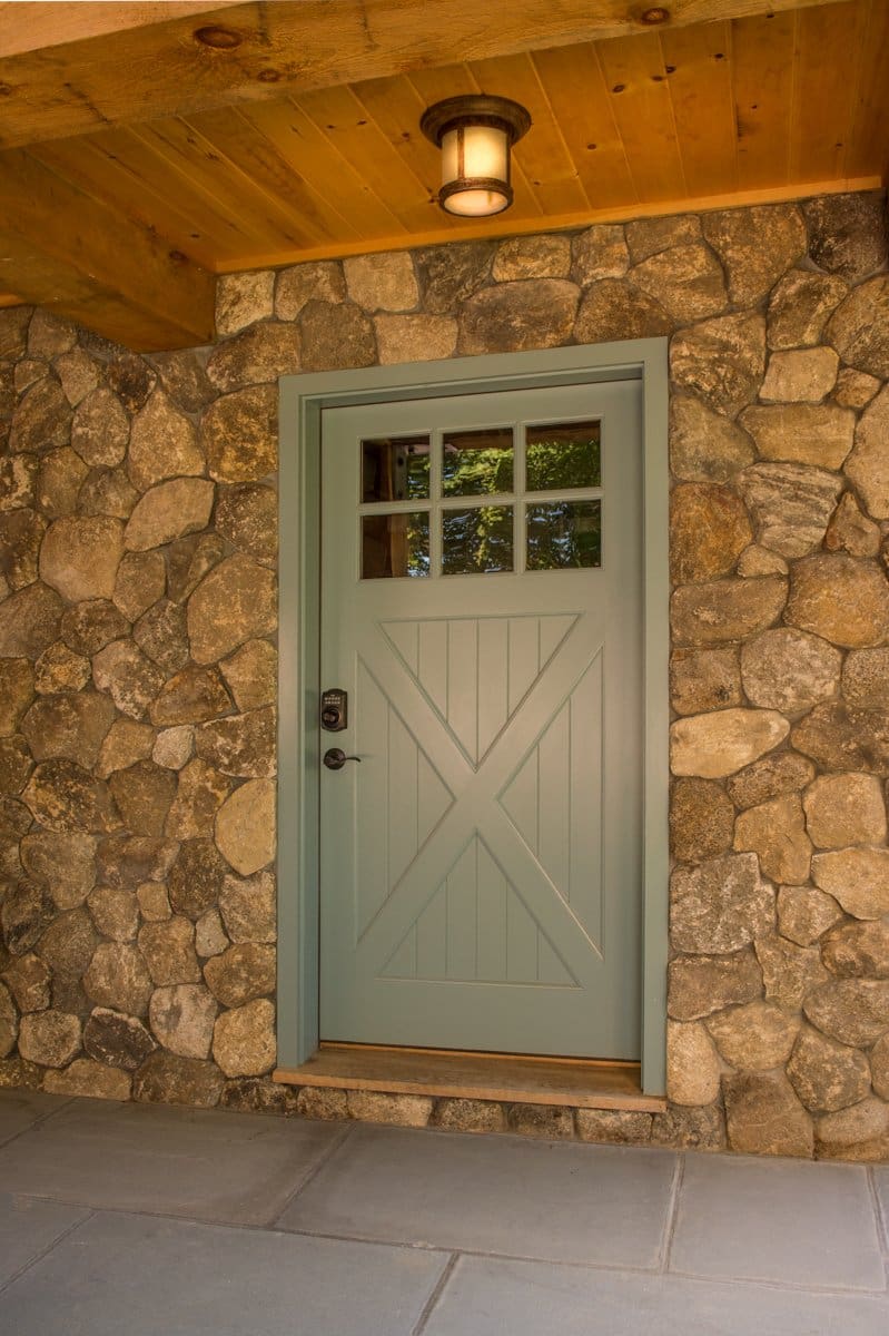 A photo of a teal-painted barn-style door in an outdoor stone wall.