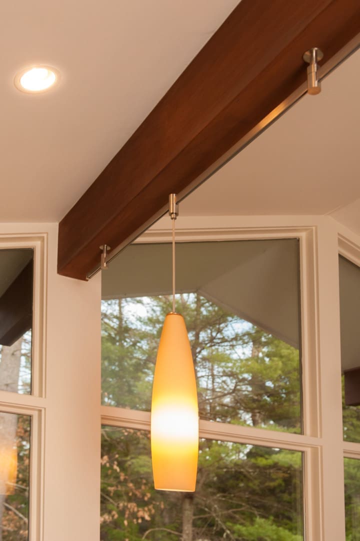 A photo of a mid-century modern light fixture hanging from a wooden beam.