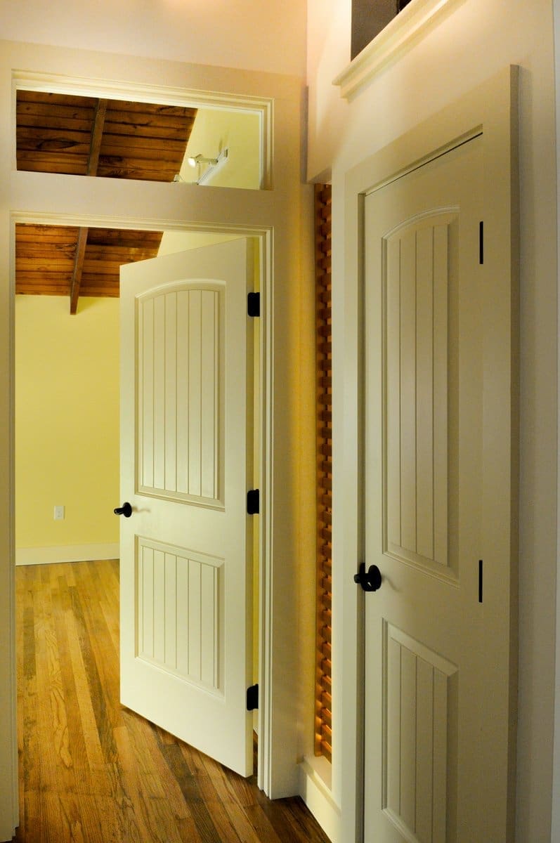 A photo of a hallway with rustic-style painted doors and rustic hardwood flooring.