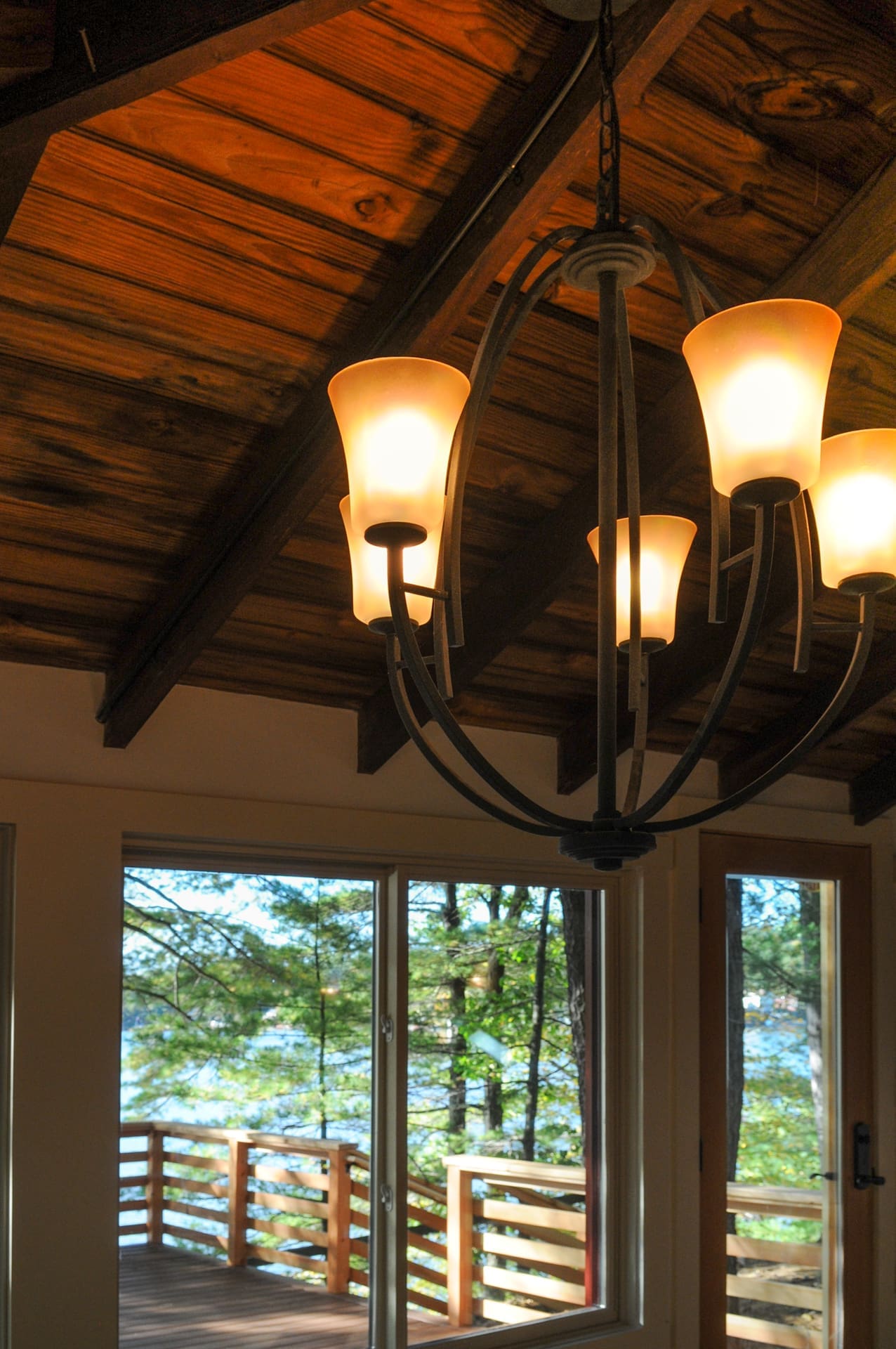 A photo of a rustic light fixture hanging from wooden vaulted ceilings.