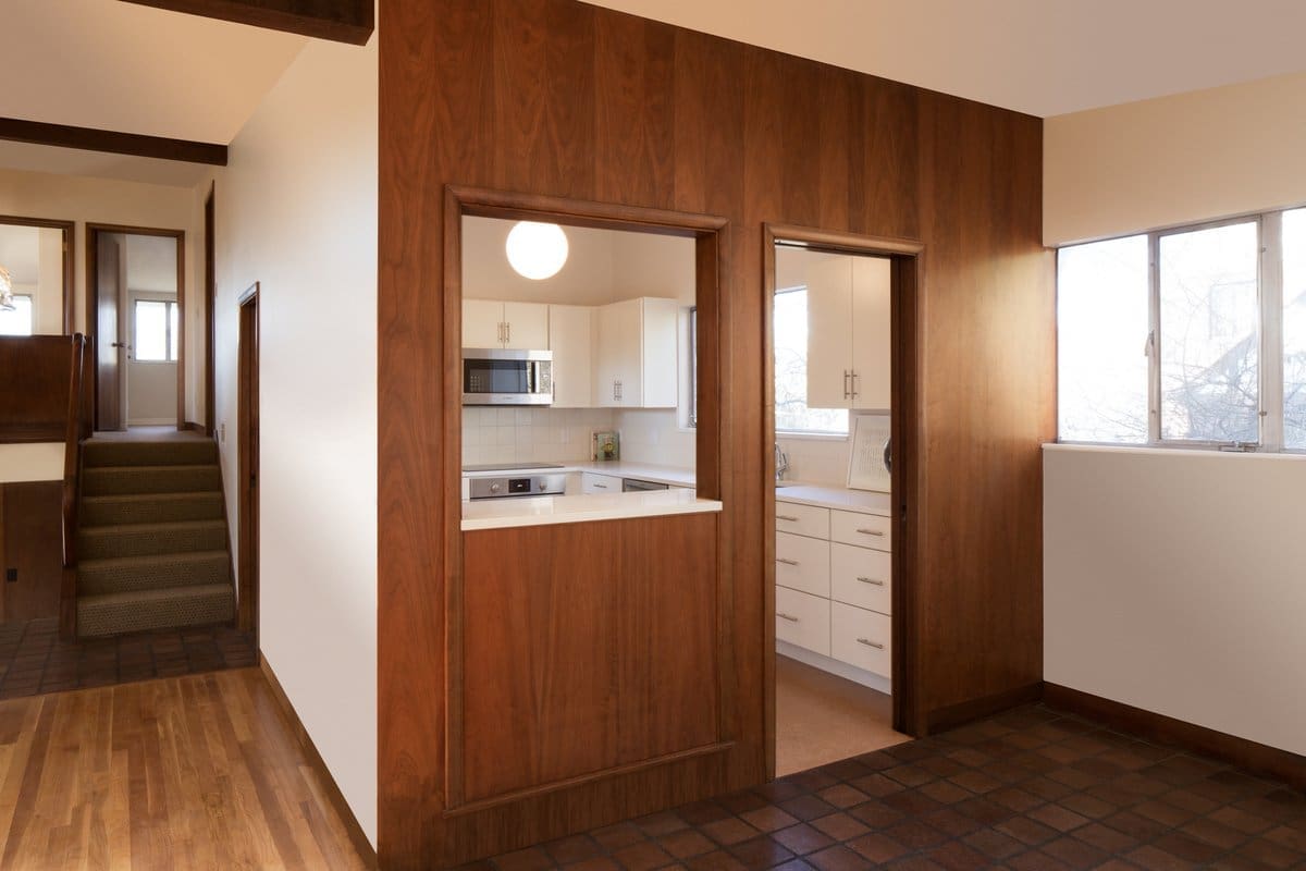 A photo of a wooden kitchen entryway with pocket door and window.
