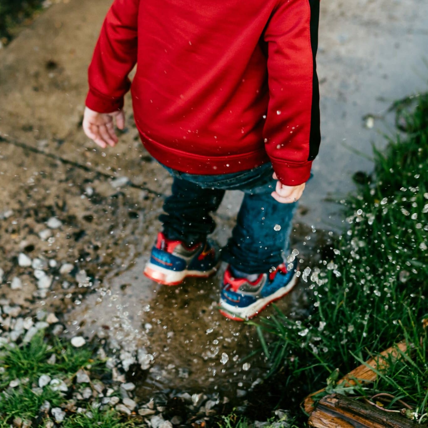 Photo of a child jumping in a puddle.