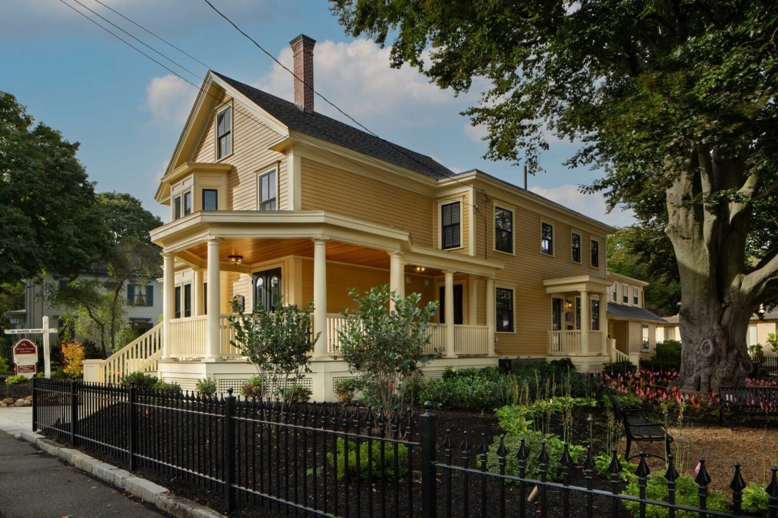 A photo of a yellow building with a front porch with yellow columns and railings.