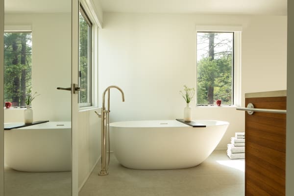 A photo of a large white soaking tub in a bathroom with brass faucets.