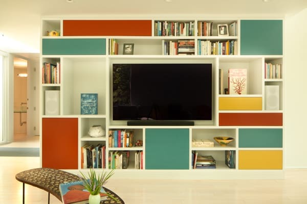 A photo of a multicolored built-in cabinet housing books and a TV.