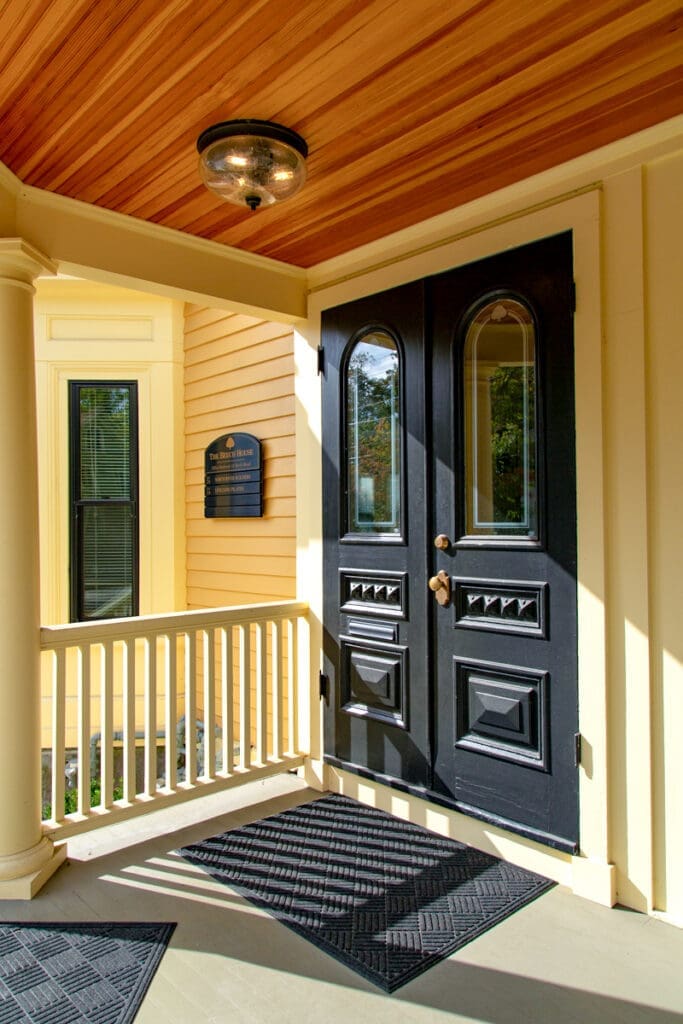 A photo of two large antique black doors, main entry into the Beech House.