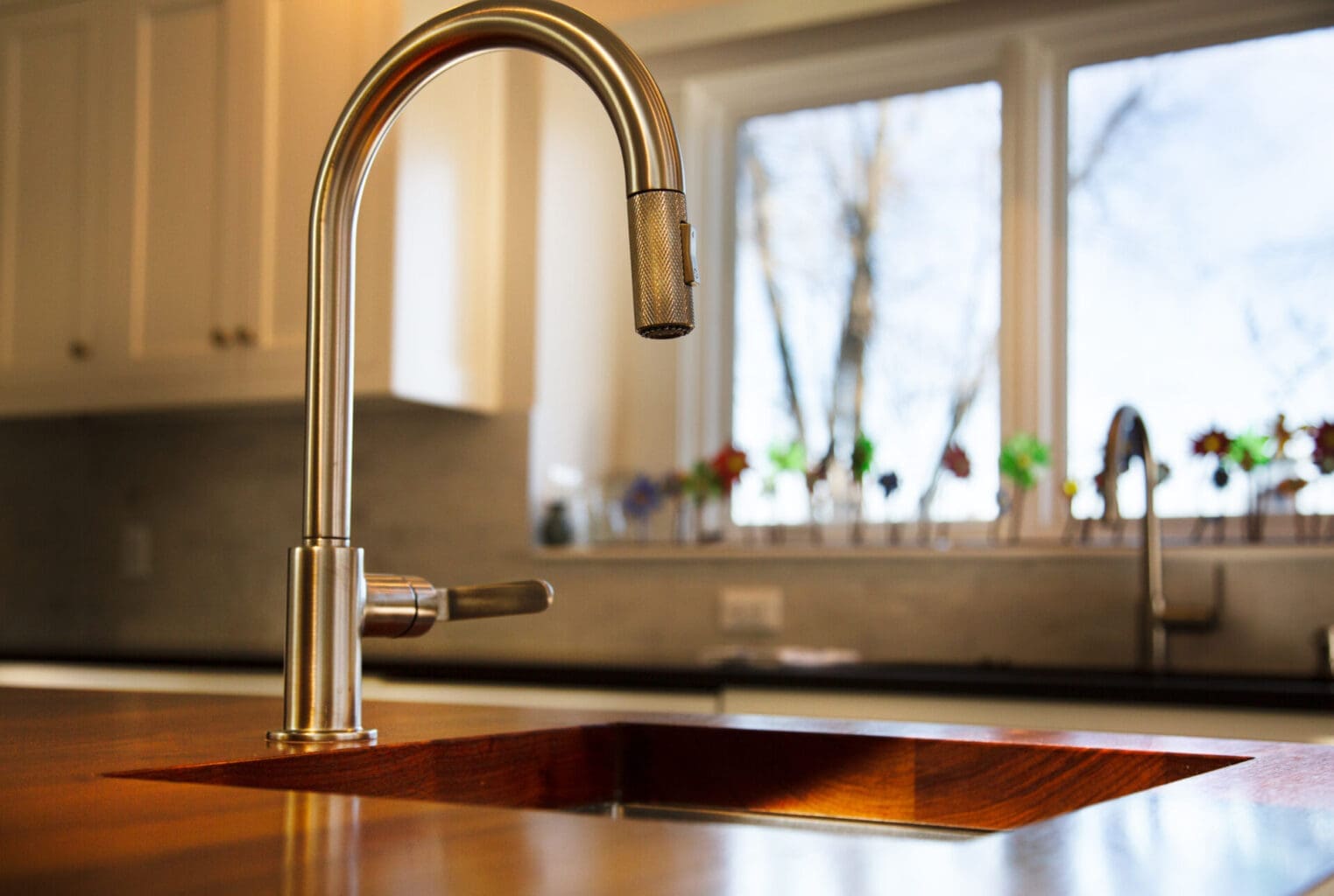 A photo of a stainless steel faucet inlaid on a wooden island.