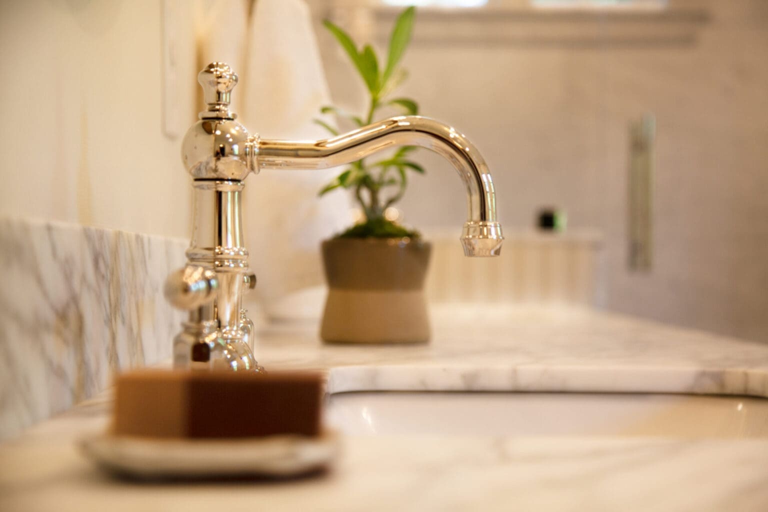 A photo of a traditional silver faucet in a bathroom with marble countertops,