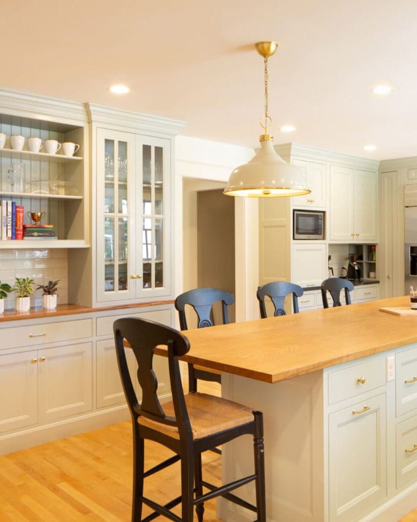 Photo of a classic grey-teal kitchen with shaker-style cabinets, brass hardware, wooden and stone countertops, and an island.