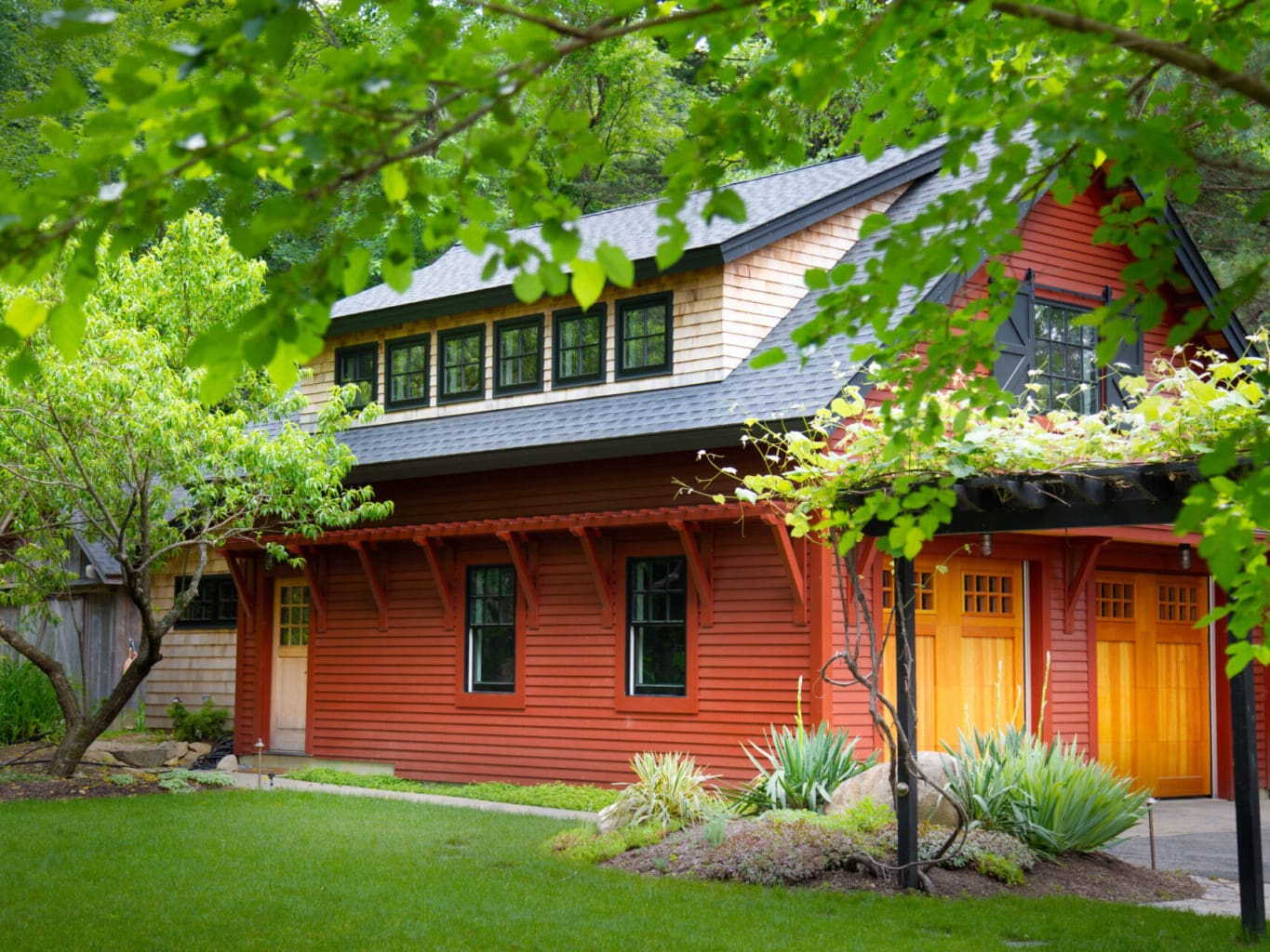 A photo of a barn-style garage with red siding, a red cedar second level, and clear vertical grain fir wooden garage doors.