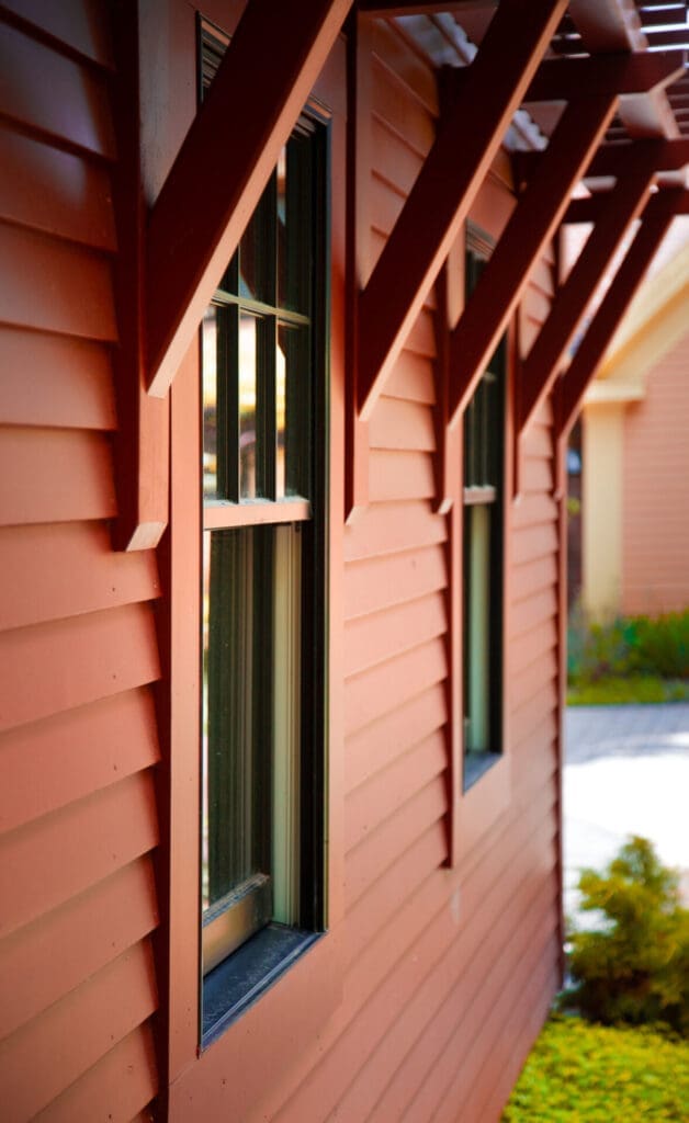 Photo of red siding and windows of a garage with diagonal support beams.