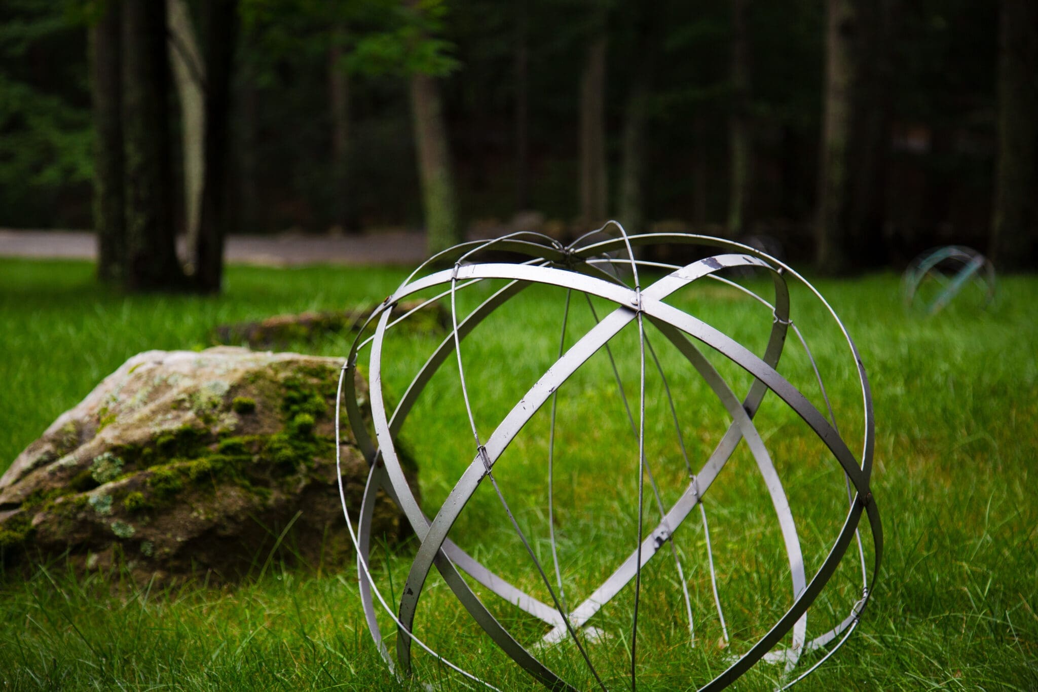 A photo of a spherical wire sculpture on a large grassy lawn.