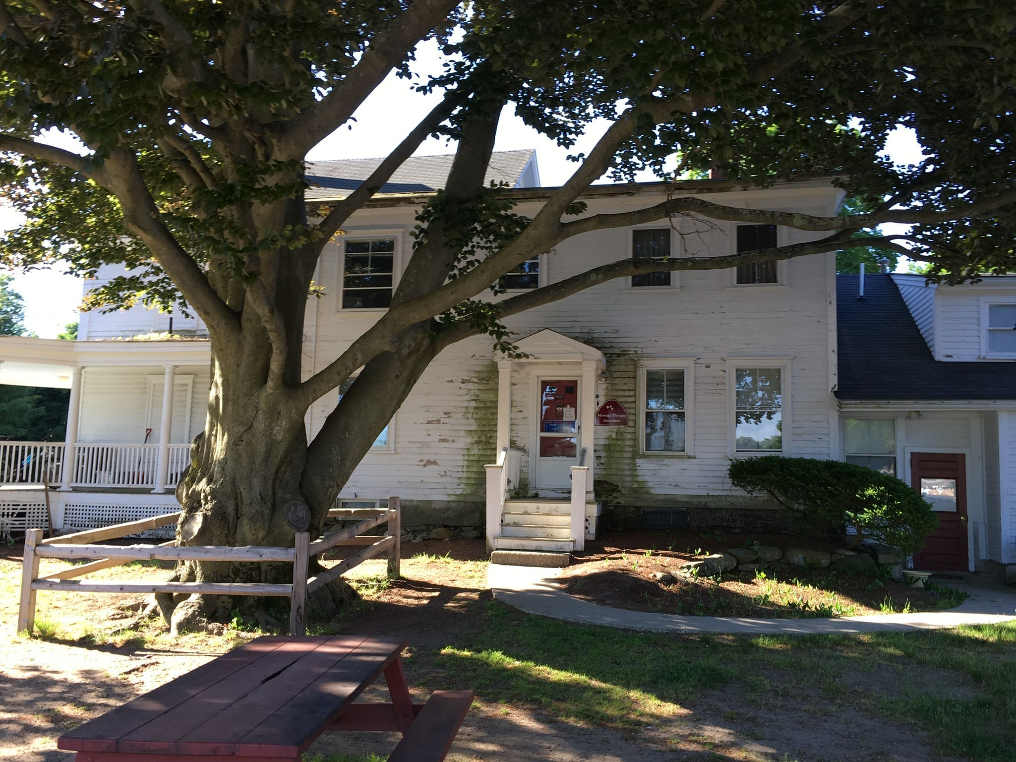 A white house with a tree in front of it.